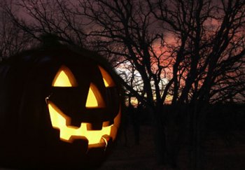 Jack-o-lantern lit up with a tree in the background at night