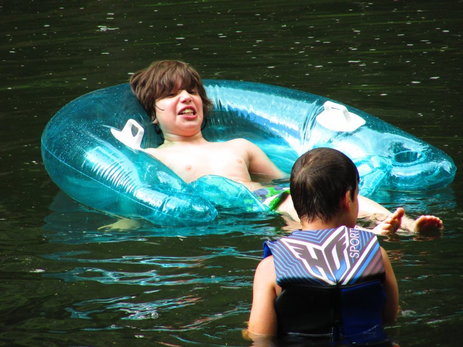 Two boys swimming in a creek